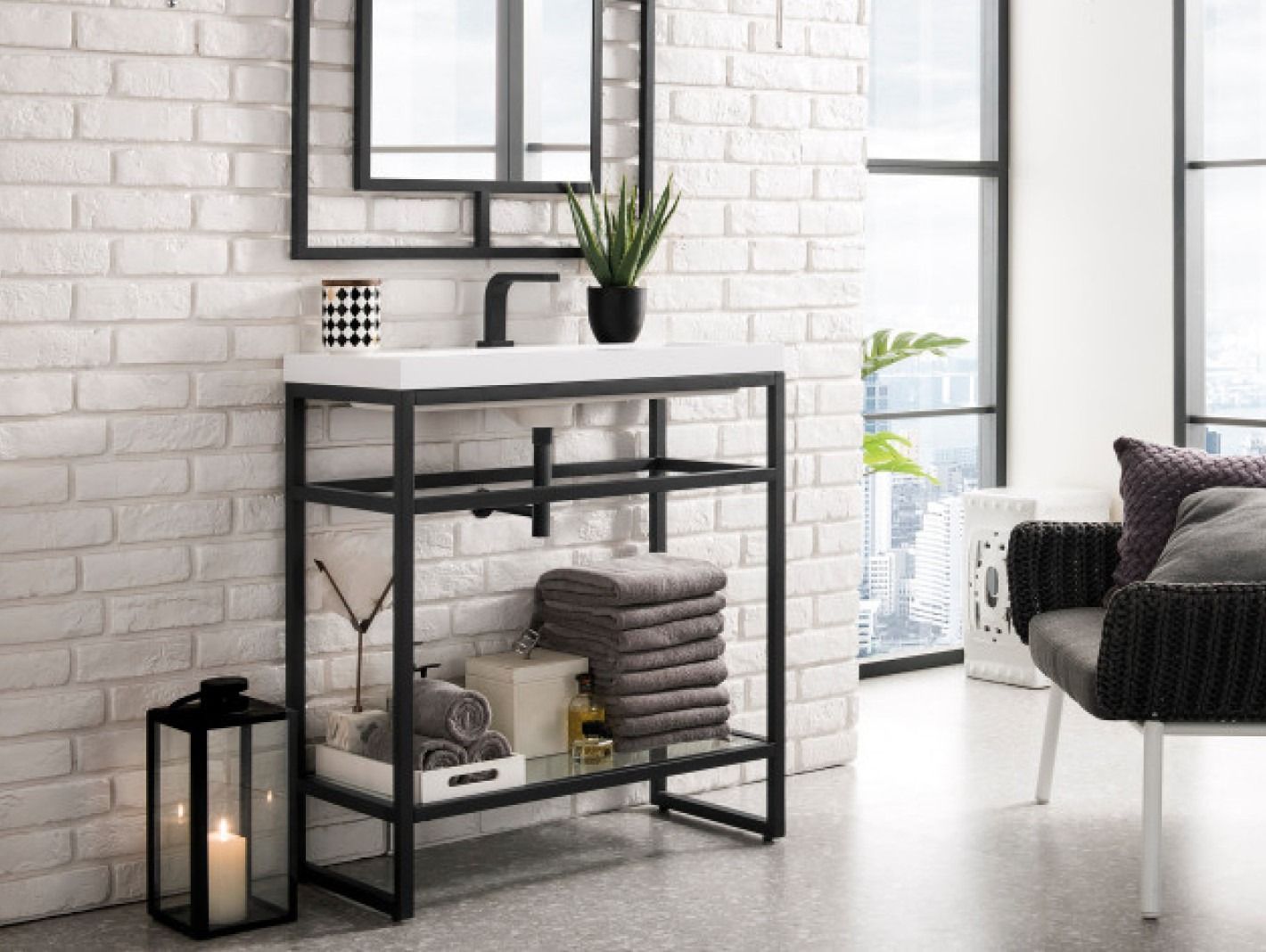Minimal white room with black console table, plant, lantern, and a wicker chair by a bright window