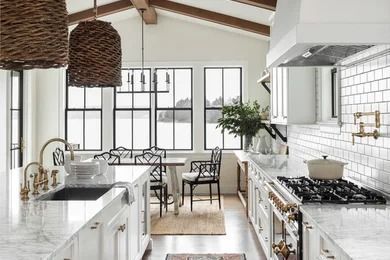 Bright white modern kitchen with island, gas range, woven pendant lights, and large windows