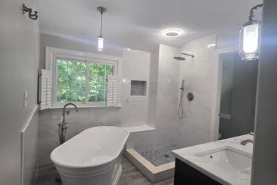 Modern white bathroom with freestanding tub, walk-in shower, window, and vanity