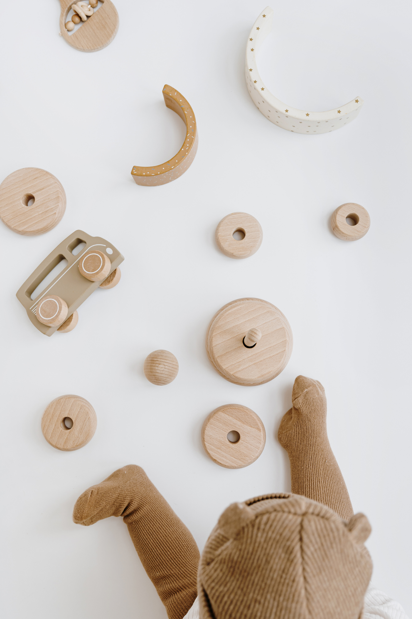 Un bébé joue avec des jouets en bois sur une surface blanche.