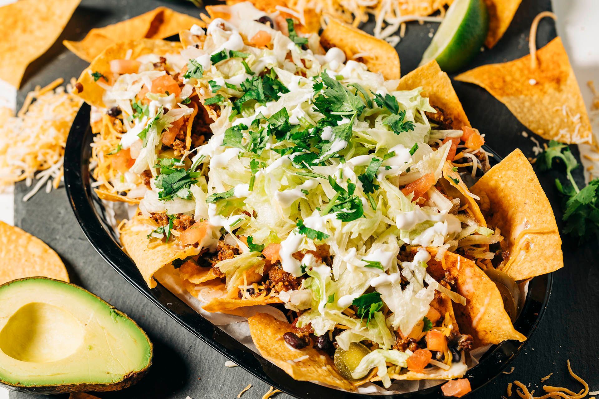 a plate of nachos with avocado on the side