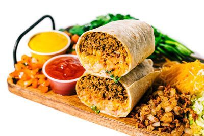 bacon cheeseburger burritos stacked on top of each other on a wooden cutting board