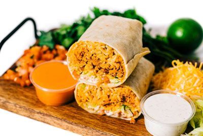 buffalo burrito stacked on top of each other on a wooden cutting board