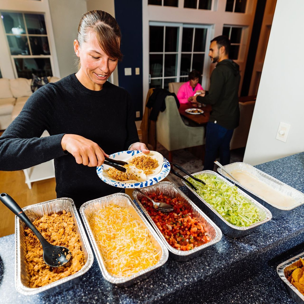 a woman is taking a plate of food from a buffet line