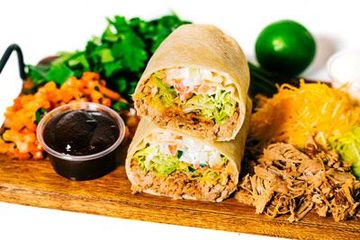 bbq pork burrito sitting on top of a wooden cutting board