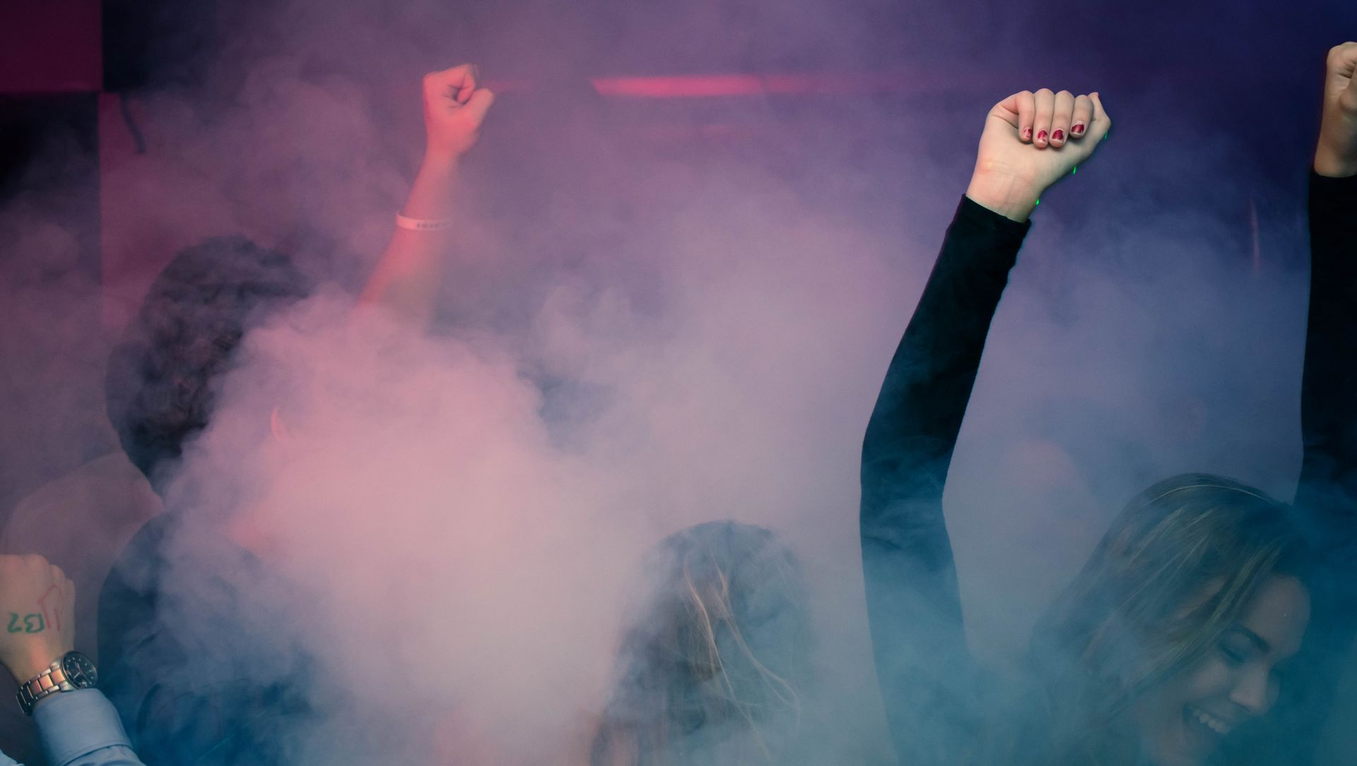 Menneskemængde med løftede næver i lyserød røg under en protest eller demonstration