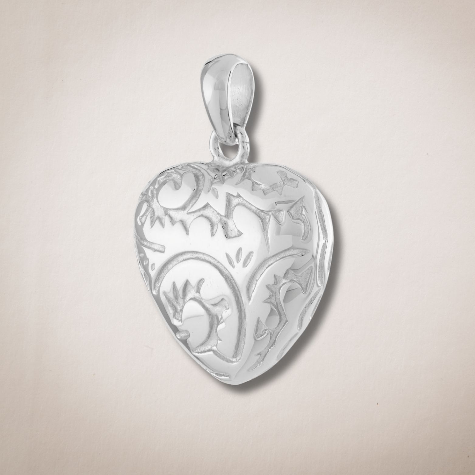 Een zilveren hanger in de vorm van een hart met een bloemenmotief erop