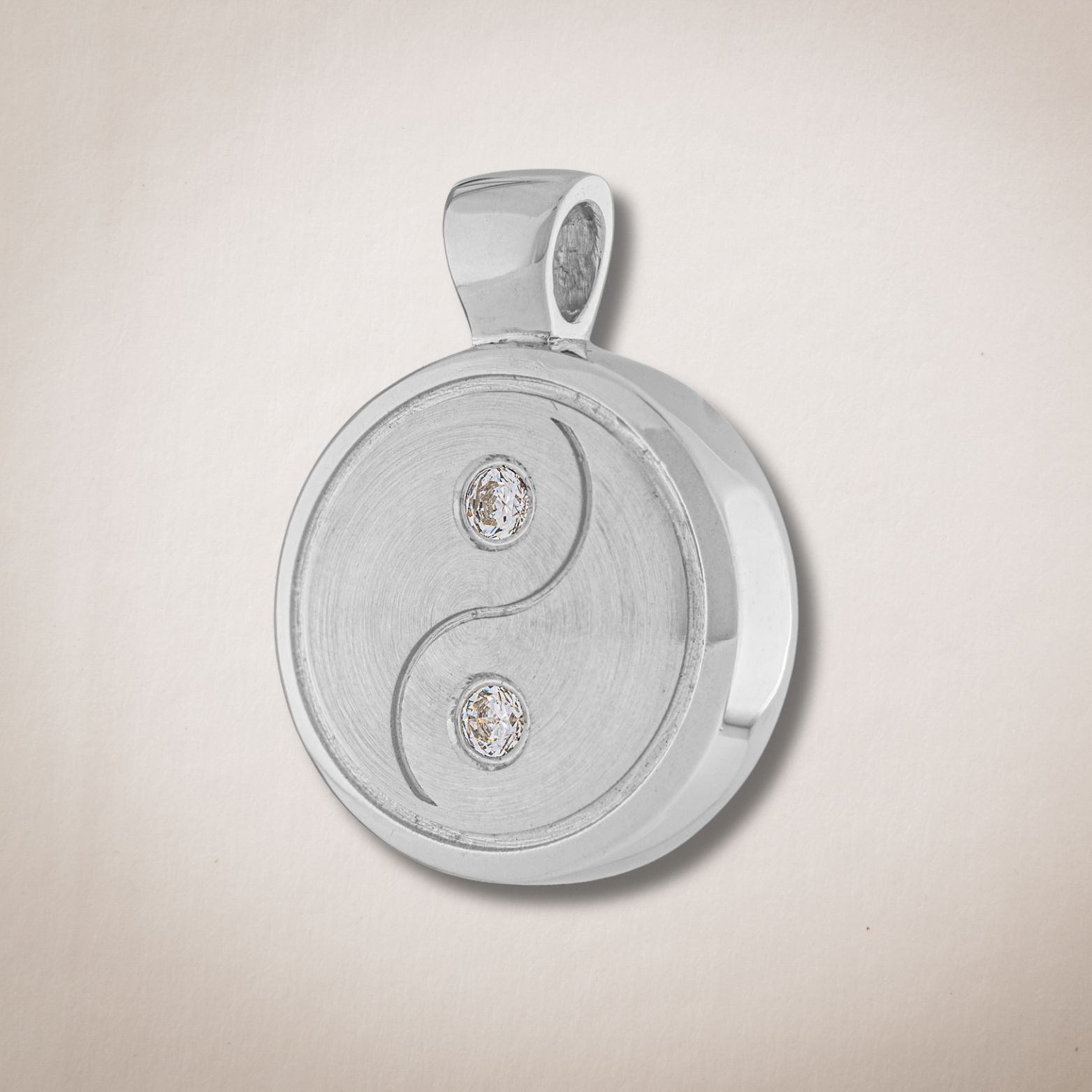 Een zilveren hanger met een yin yang symbool erop