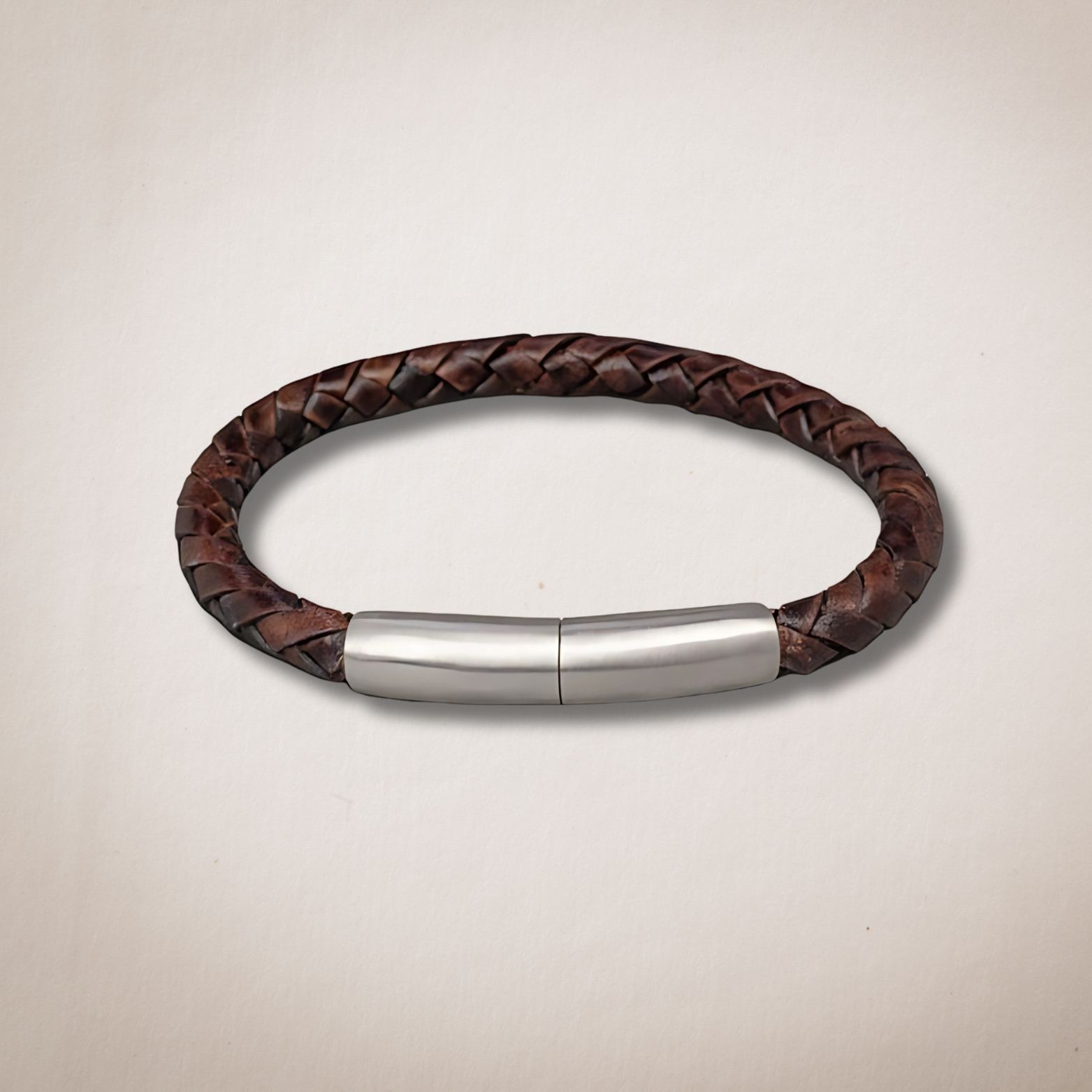 Een bruine gevlochten leren armband met een roestvrijstalen sluiting