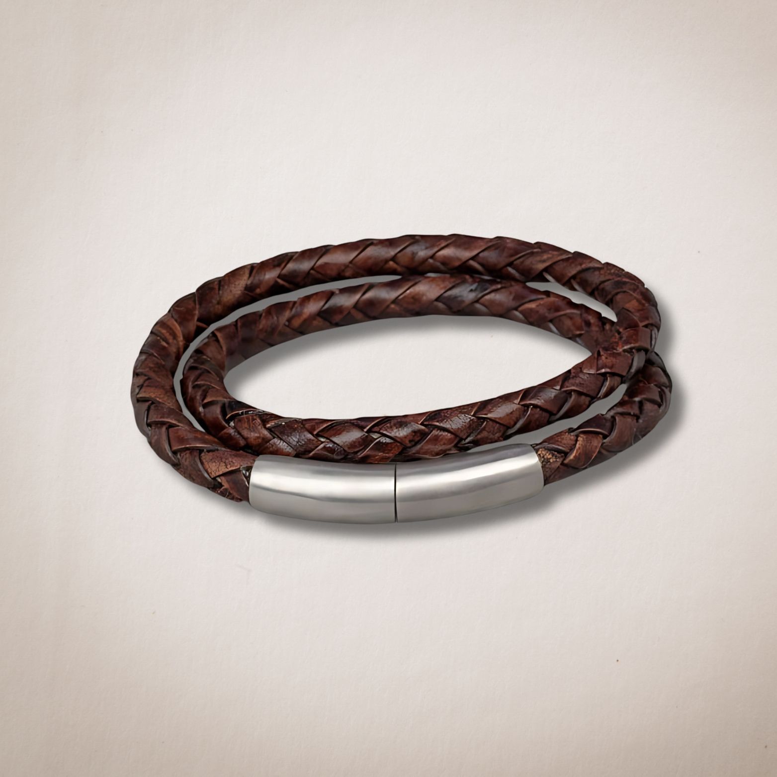 Een bruine gevlochten leren armband met een roestvrijstalen sluiting