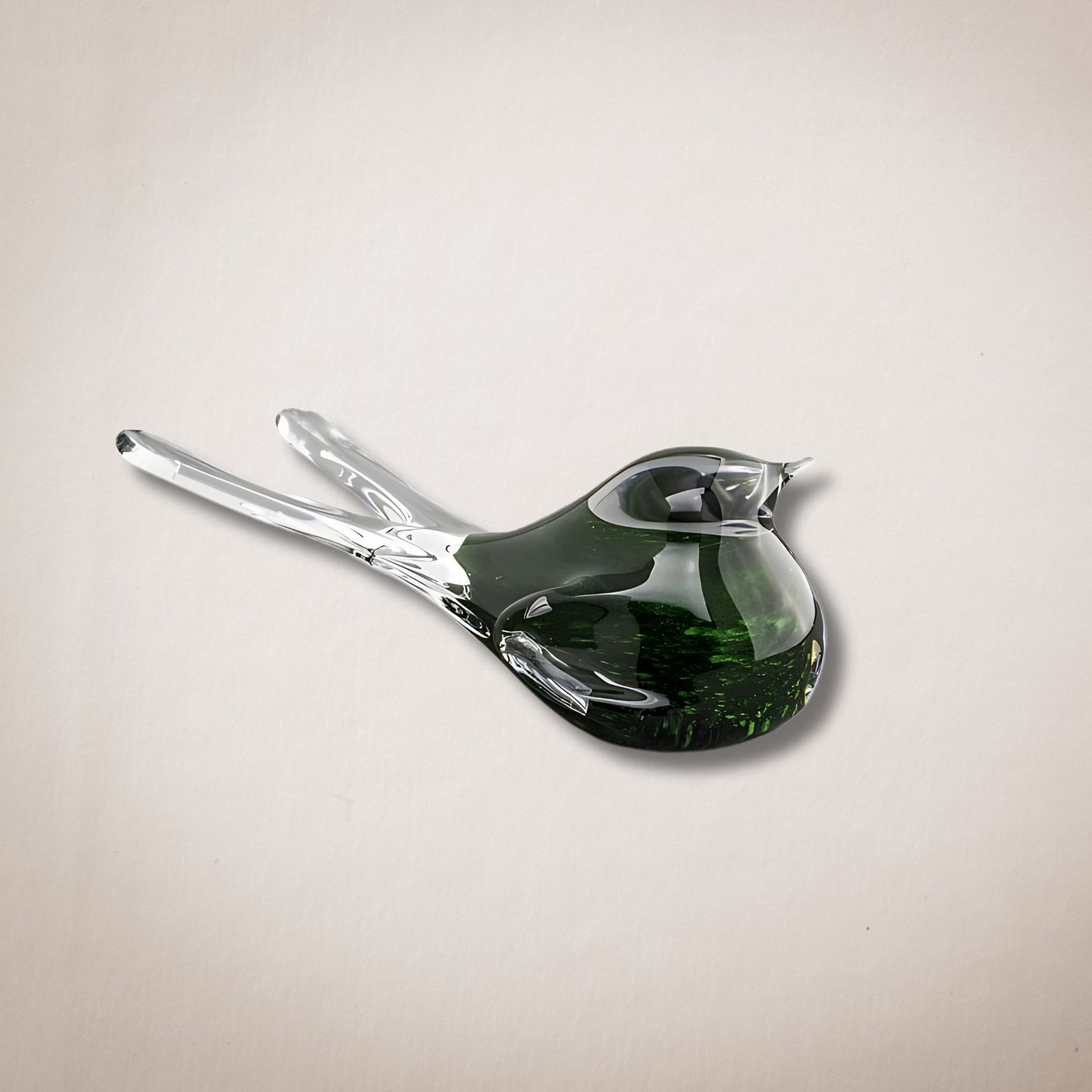 Een groene glazen vogel zit op een wit oppervlak
