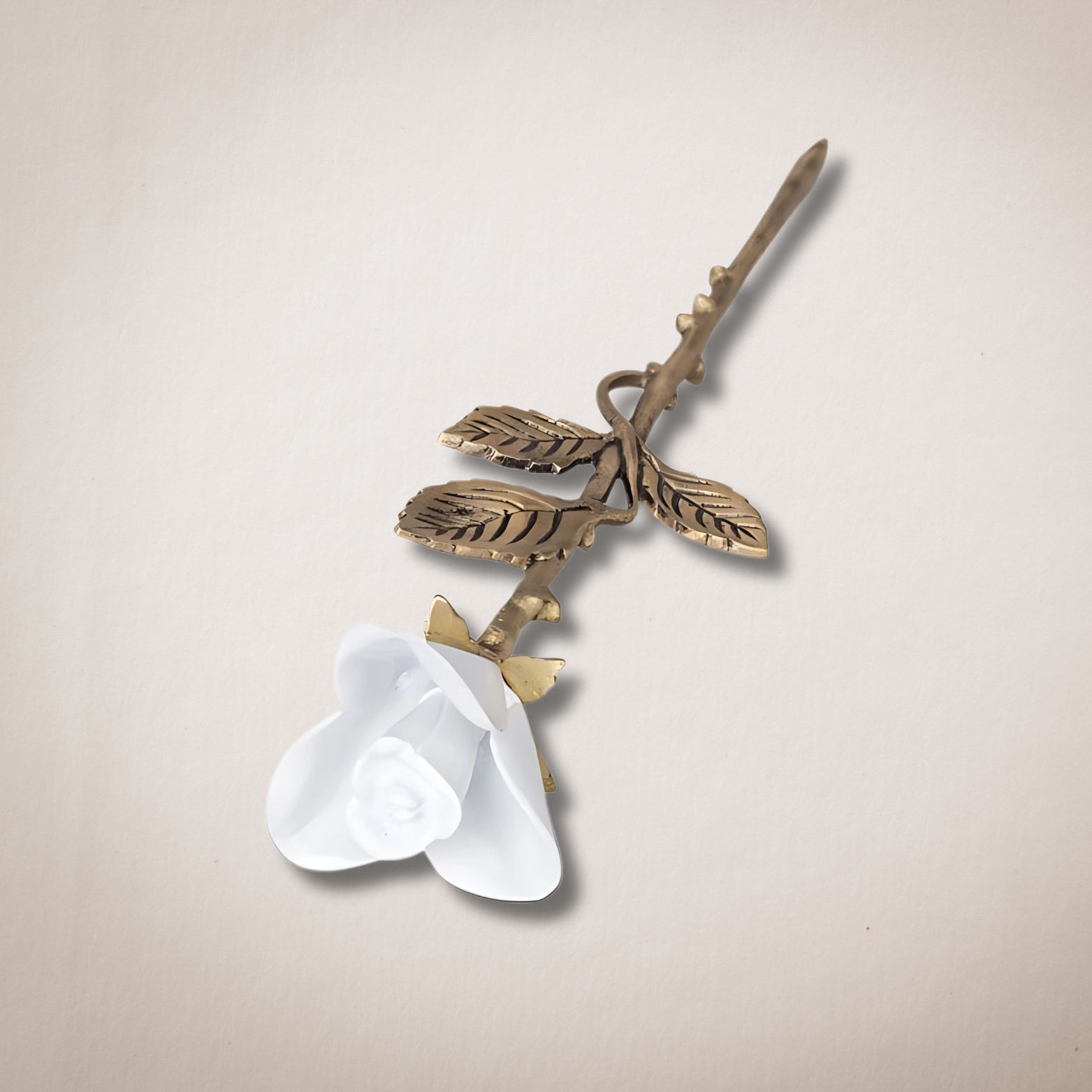 Een witte roos met gouden bladeren op een witte achtergrond