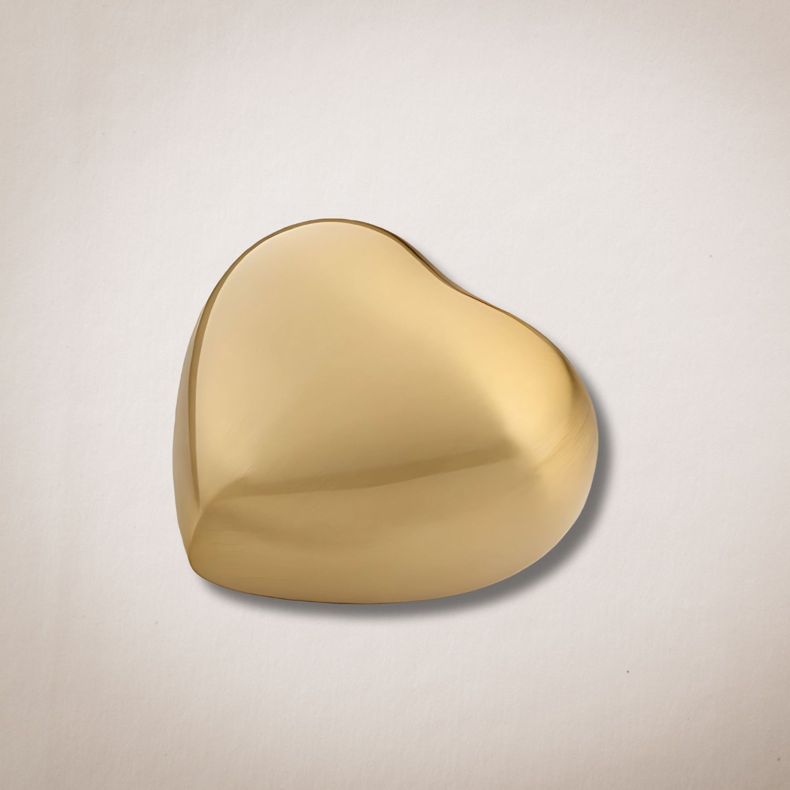 Een gouden hartvormig voorwerp ligt op een wit oppervlak