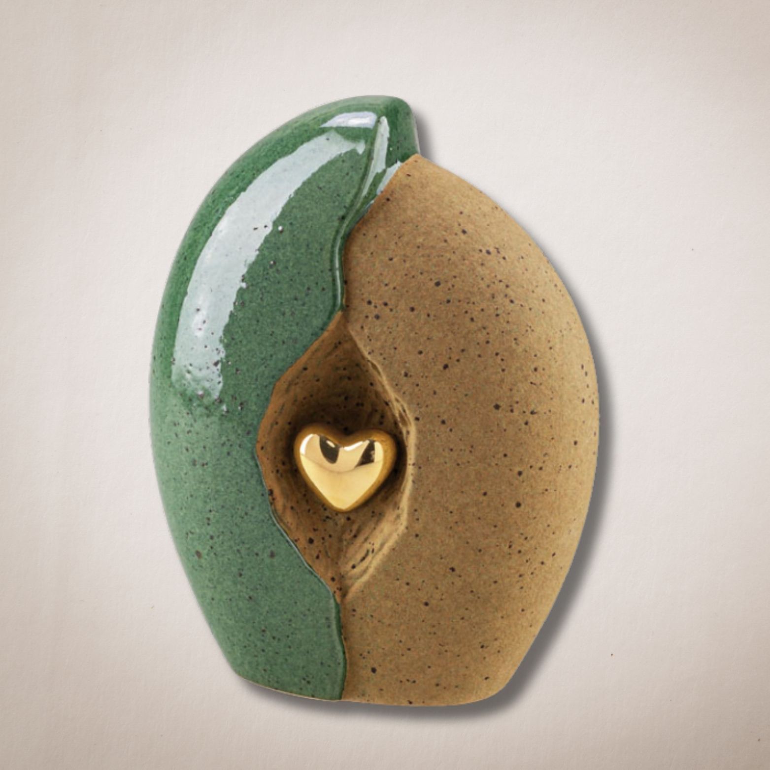 Een groen en bruin keramisch beeld met een gouden hart in het midden
