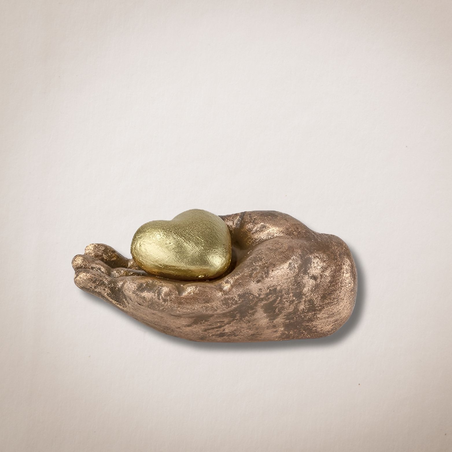 Een bronzen beeld van een hand die een gouden hart vasthoudt