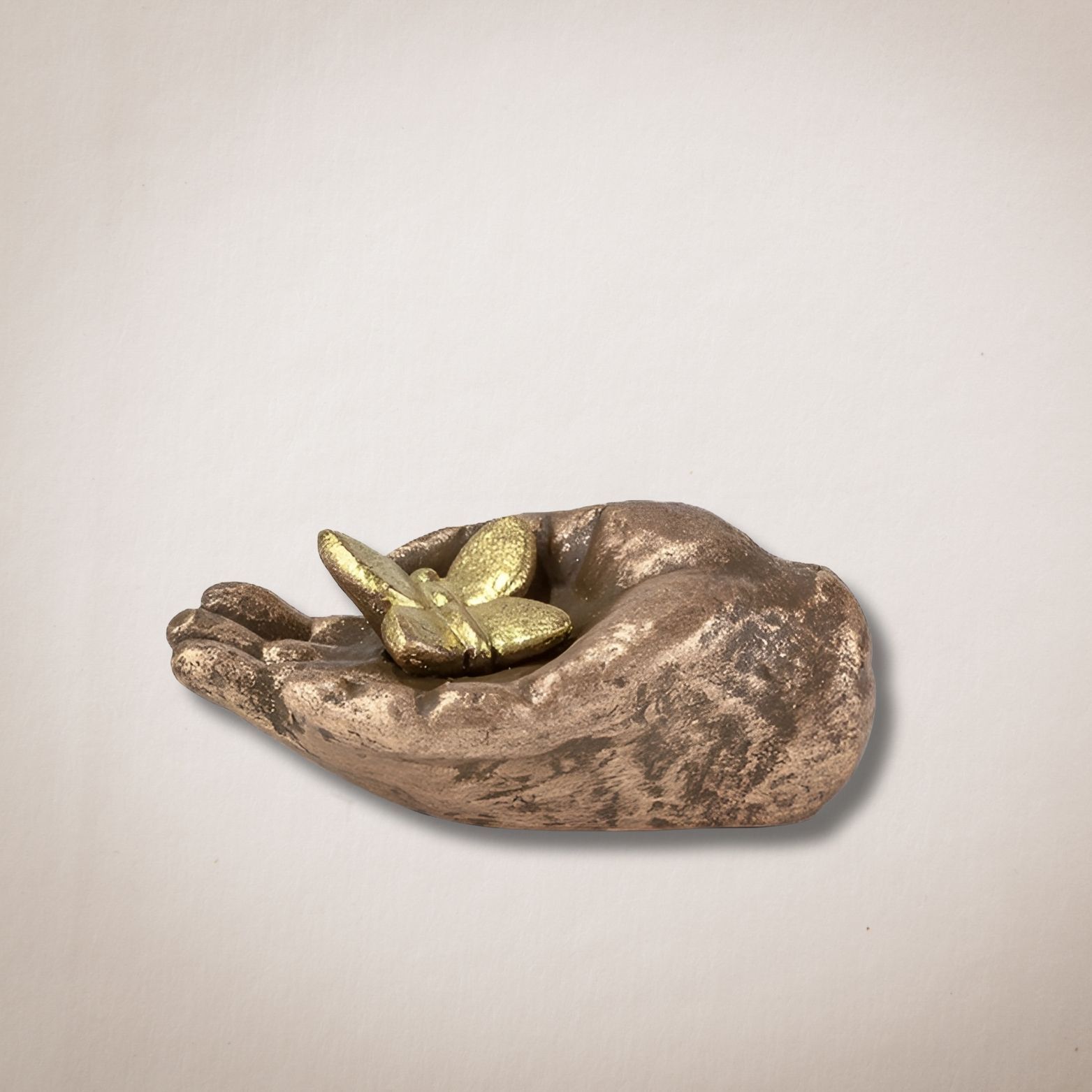 Een bronzen beeld van een hand die een vlinder vasthoudt