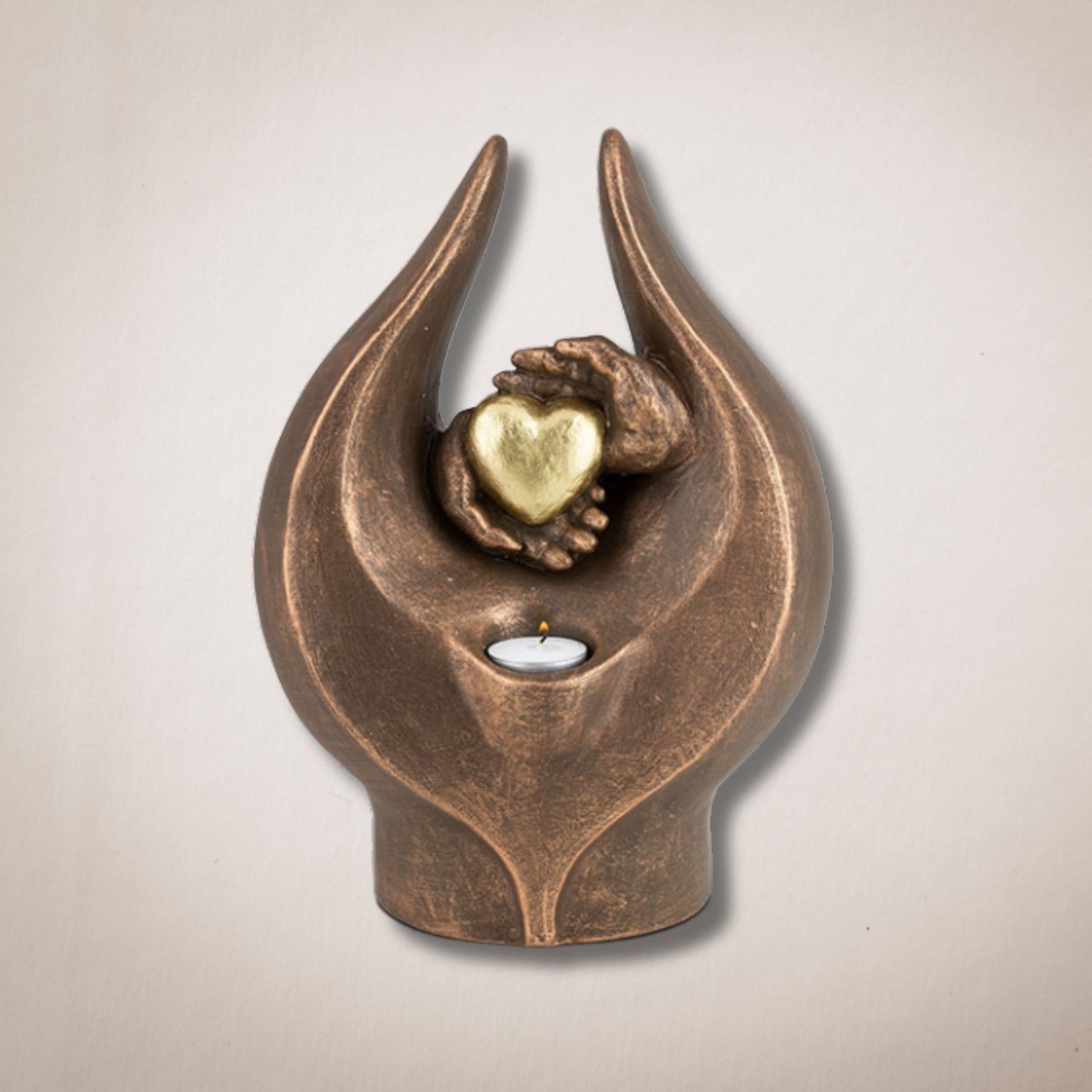 Een bronzen beeld van twee handen die een hart en een kaars vasthouden