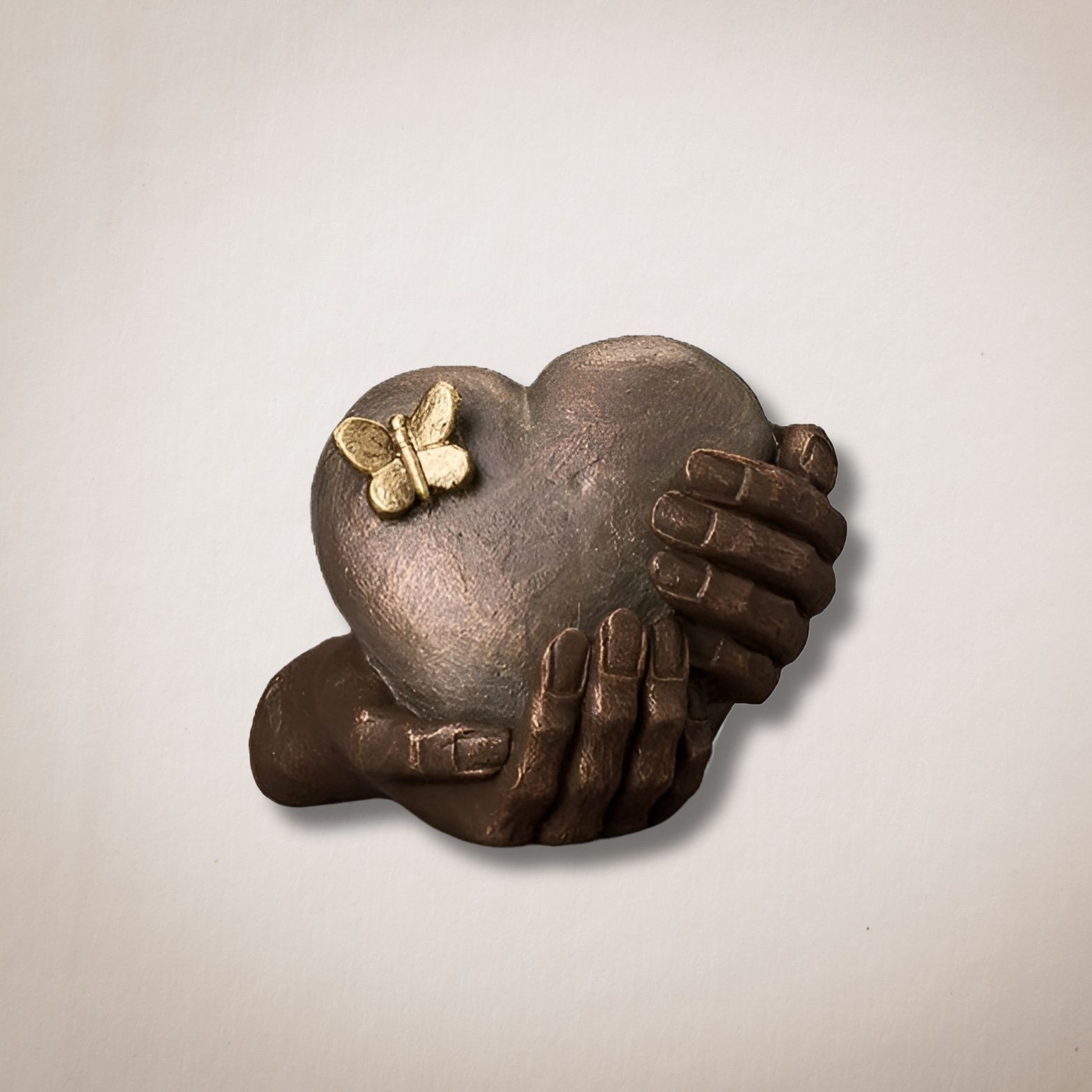 Een bronzen beeld van twee handen die een hart met een vlinder erop vasthouden.
