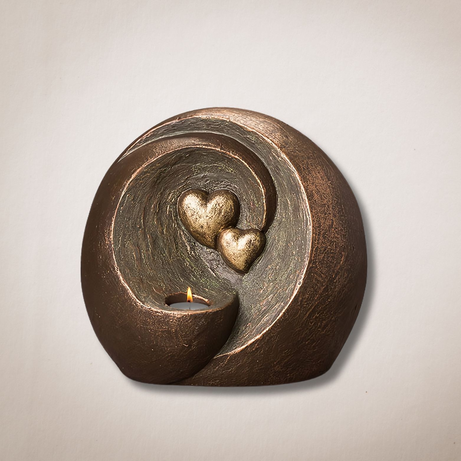 Een bronzen beeld met daarin twee harten en een kaars