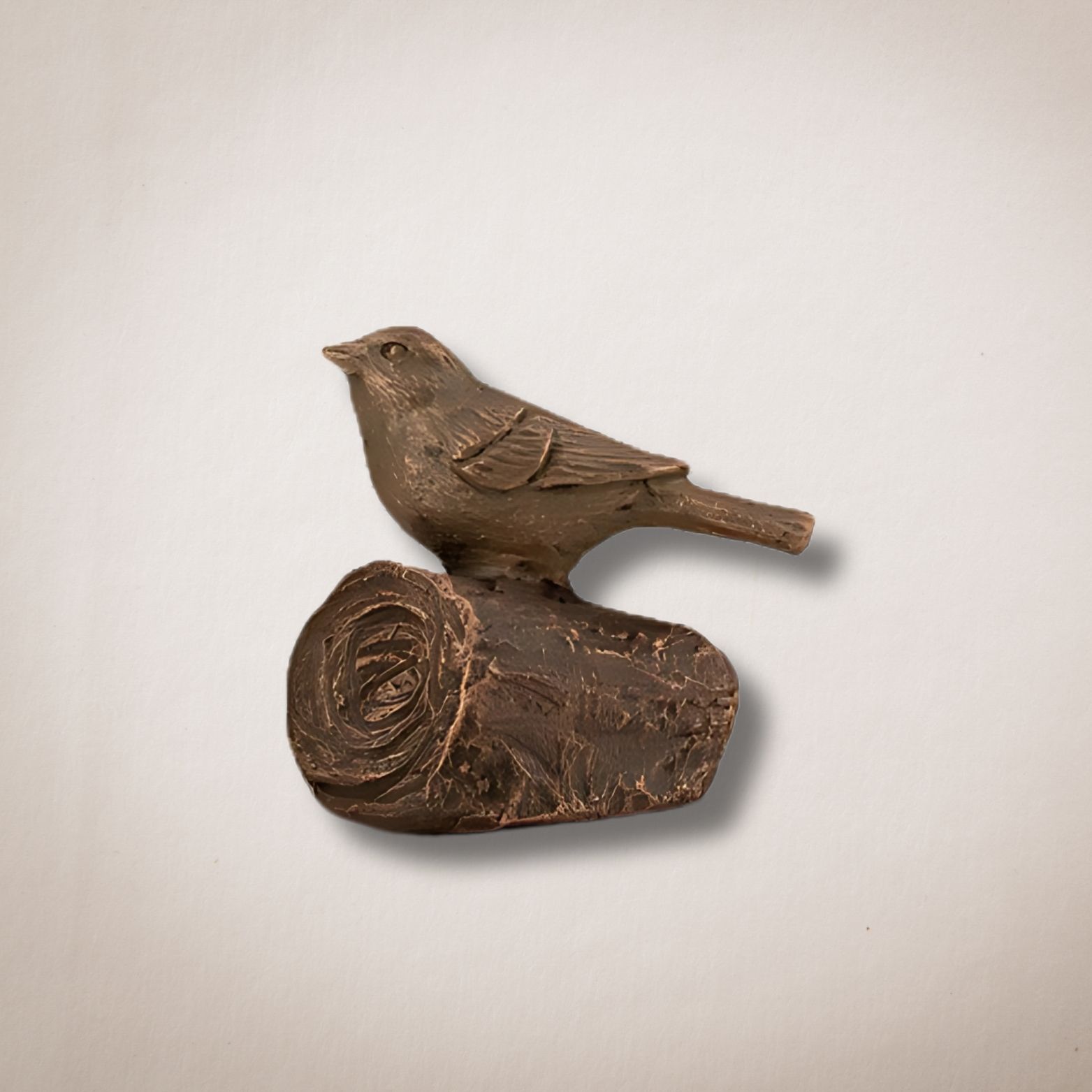 Een bronzen beeld van een vogel die op een boomstam zit
