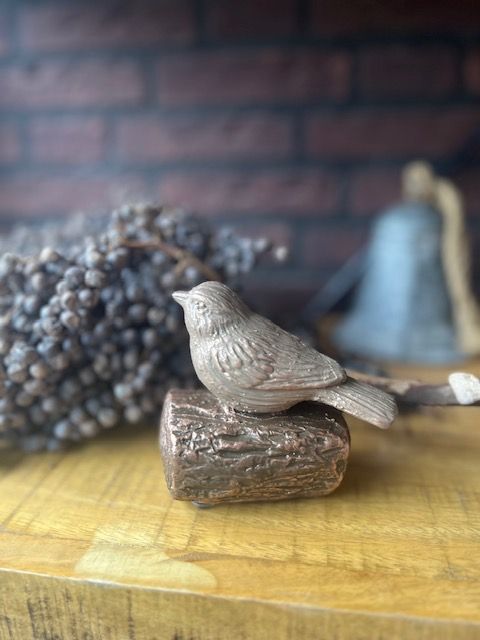 Een bronzen beeld van een vogel die op een boomstam zit