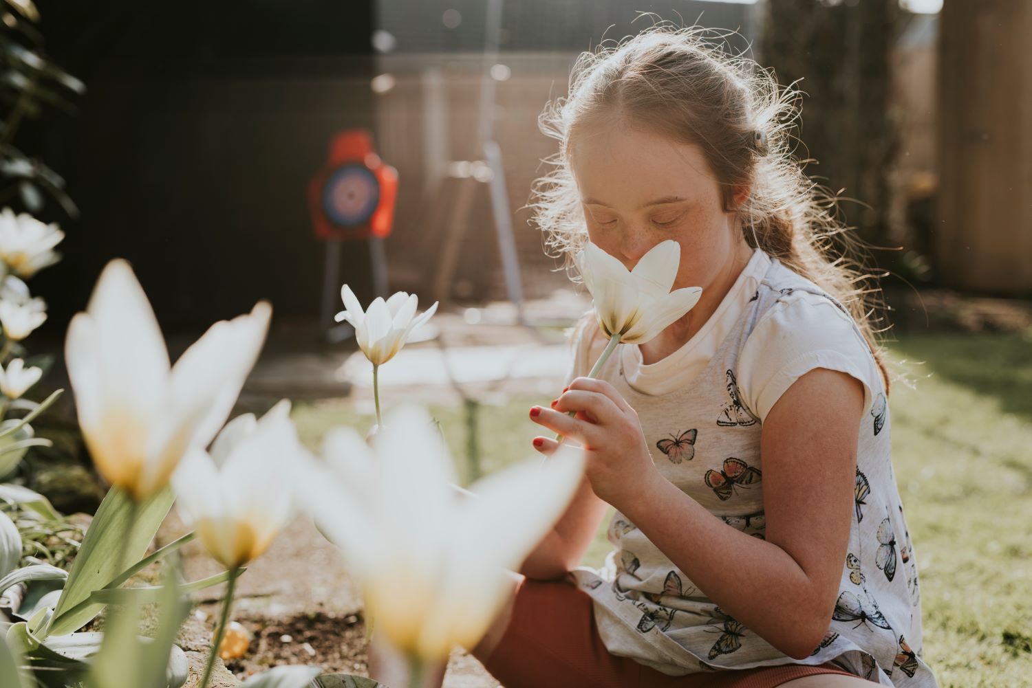 Down Syndrome Girl Smelling Flower — Eleos Support Services In Lavington, NSW