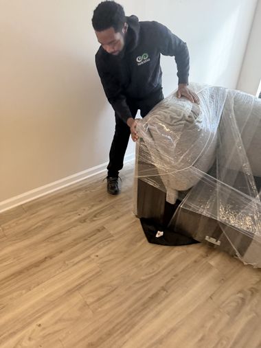 Three movers in matching black company shirts stand in and near an open moving truck outdoors.