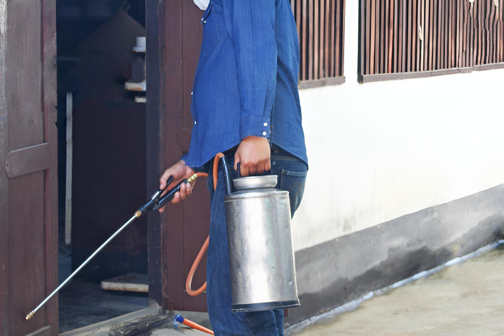 Man is Spraying a Building With Facemask — Shark Pest Control in Peregian Beach, QLD