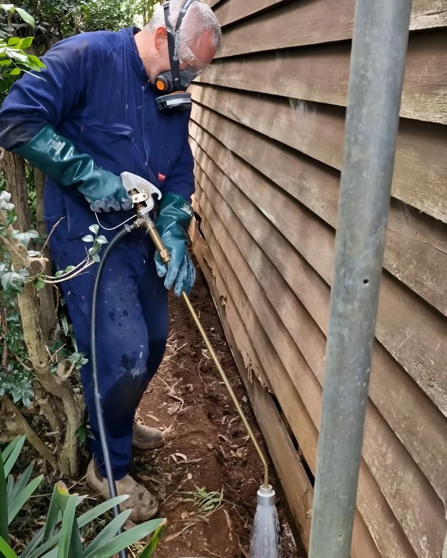 Man in a Blue Jumpsuit is Spraying on Wood — Shark Pest Control in Warana, QLD