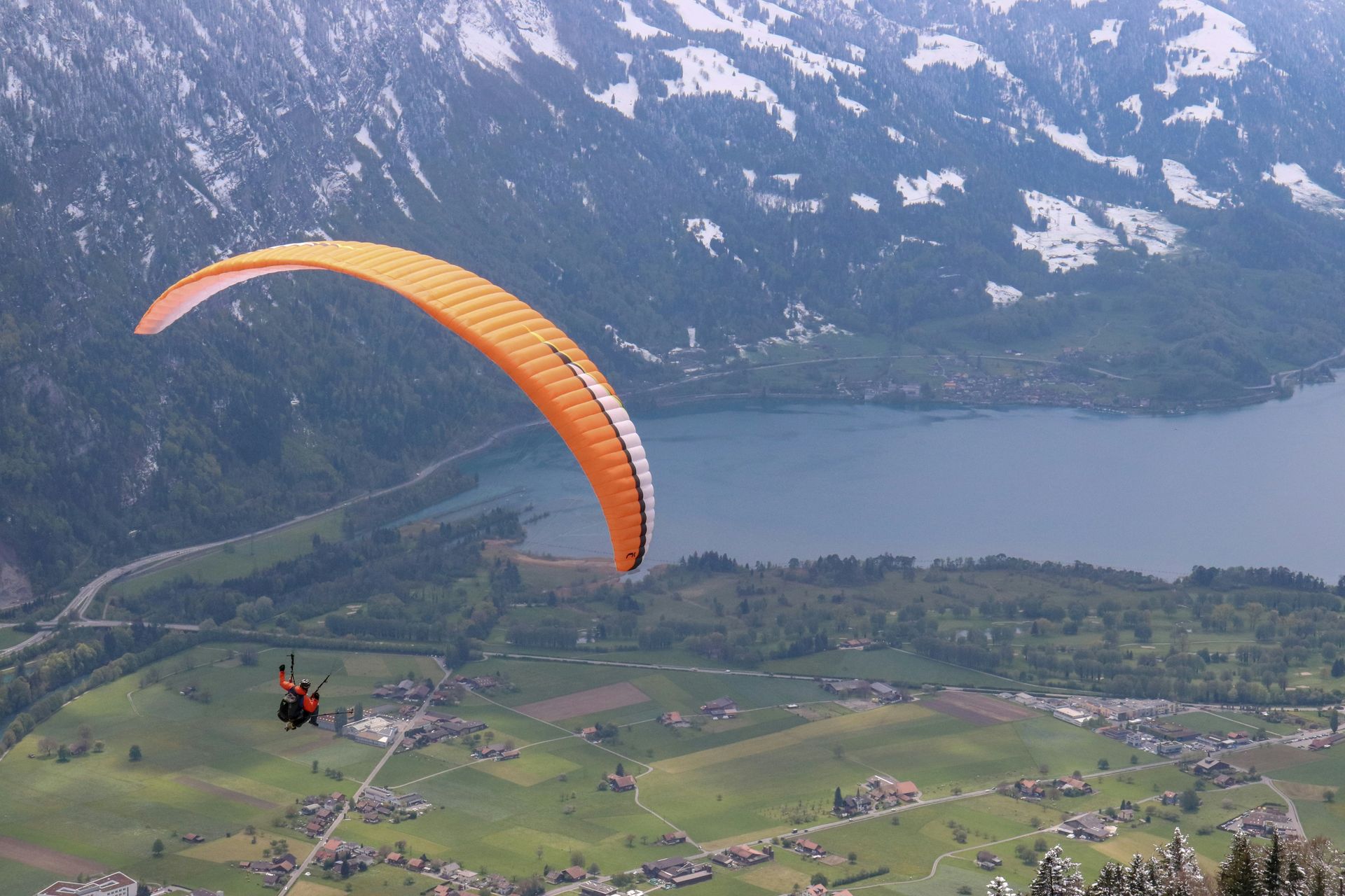 A person is parasailing over a lake in the mountains.