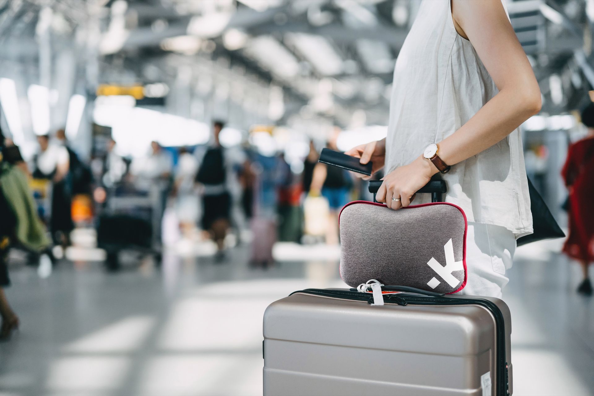 A woman is carrying a suitcase and a purse at an airport.
