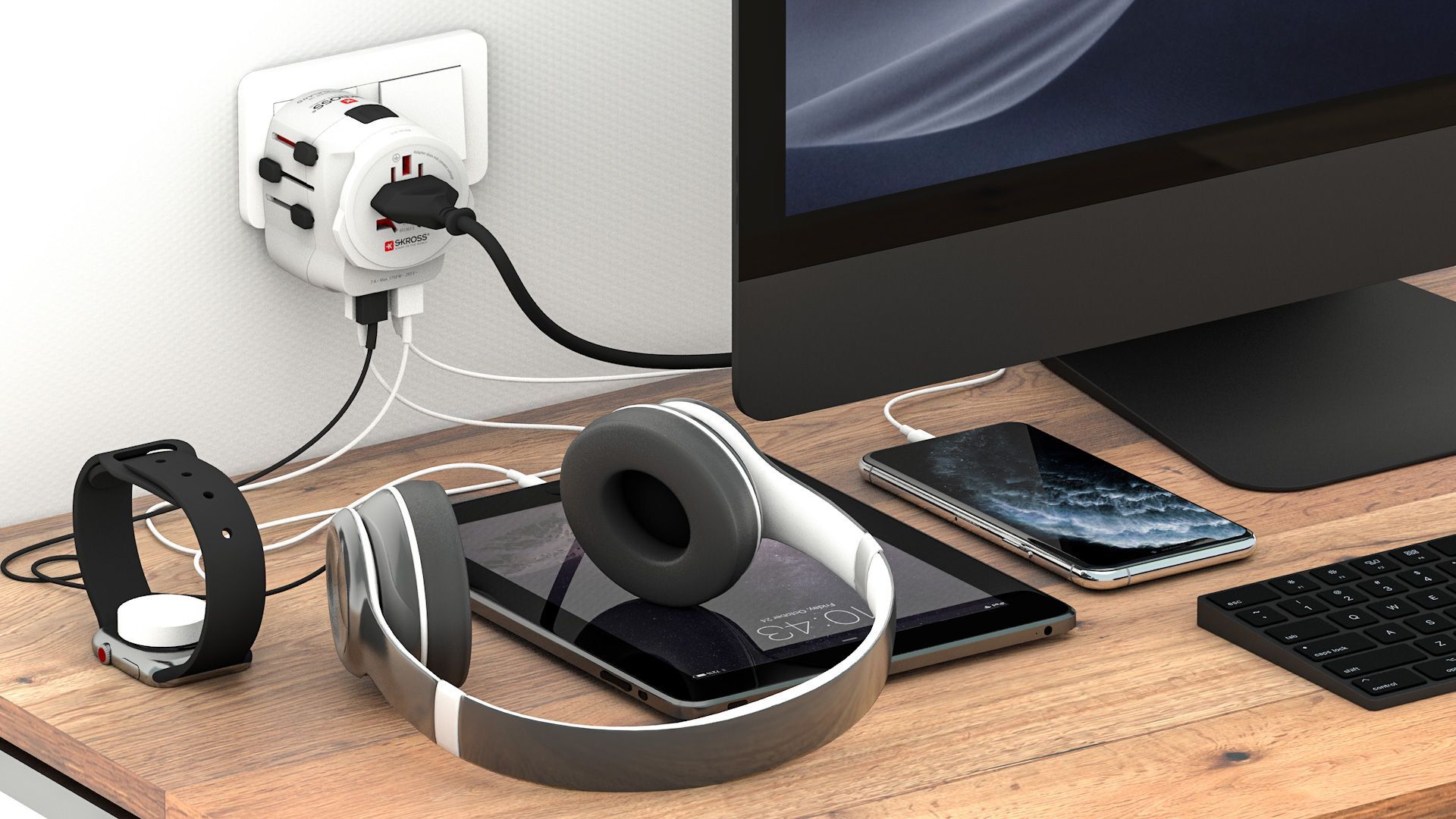 A desk with a computer , headphones , a watch , a tablet , and a phone.