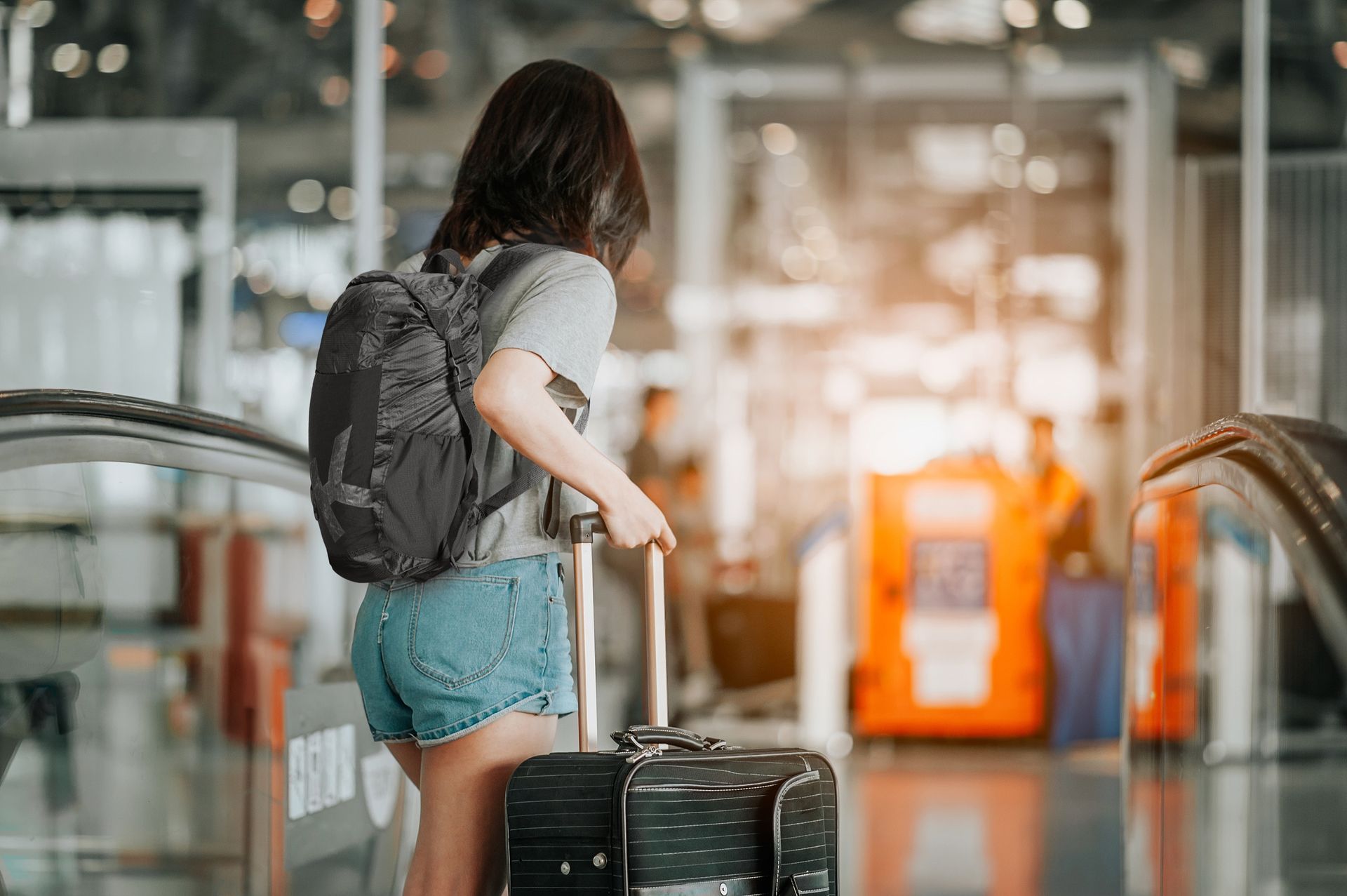 A woman with a Skross backpack is walking with a suitcase at an airport.