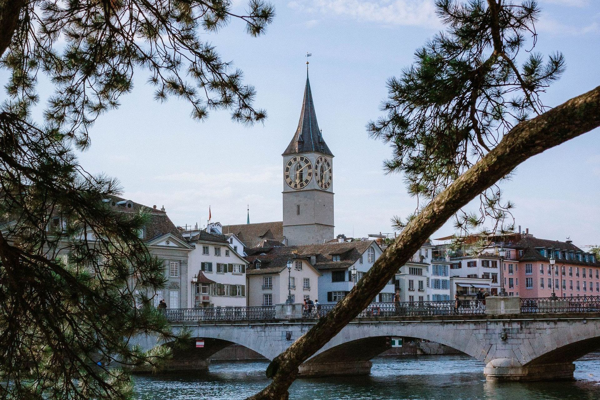 A bridge over a river with a clock tower in the background