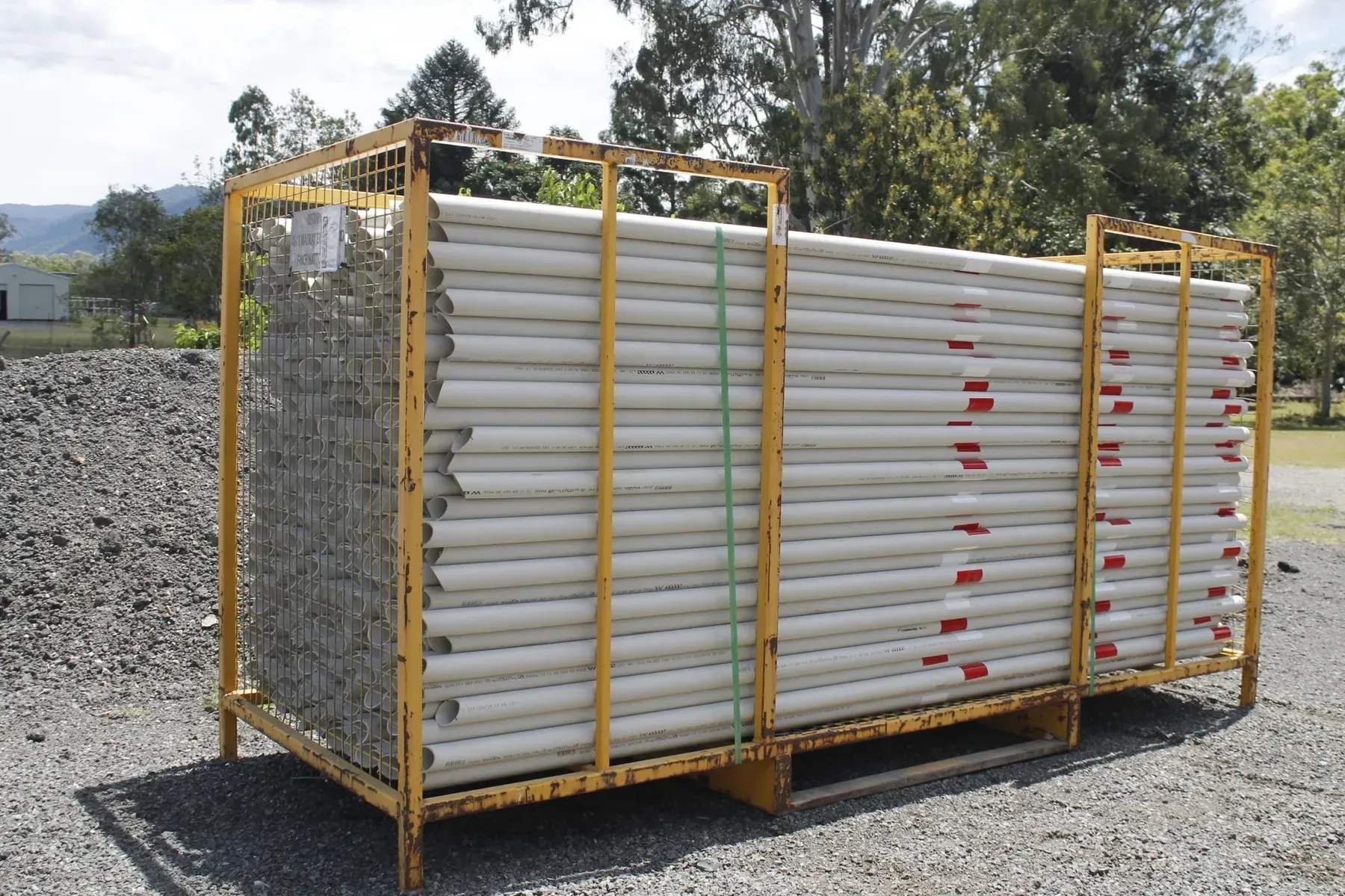 Yellow Metal Cage Containing Stacked White Pipes — Jemal Enterprises In Finch Hatton, QLD