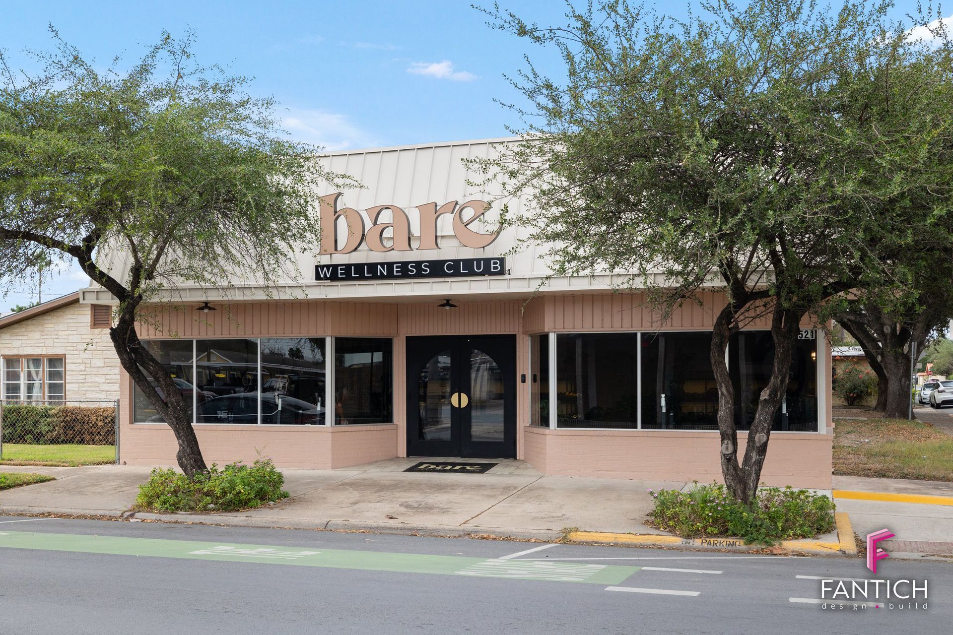 Small storefront with a “bar” sign, glass windows, and trees along a quiet street.