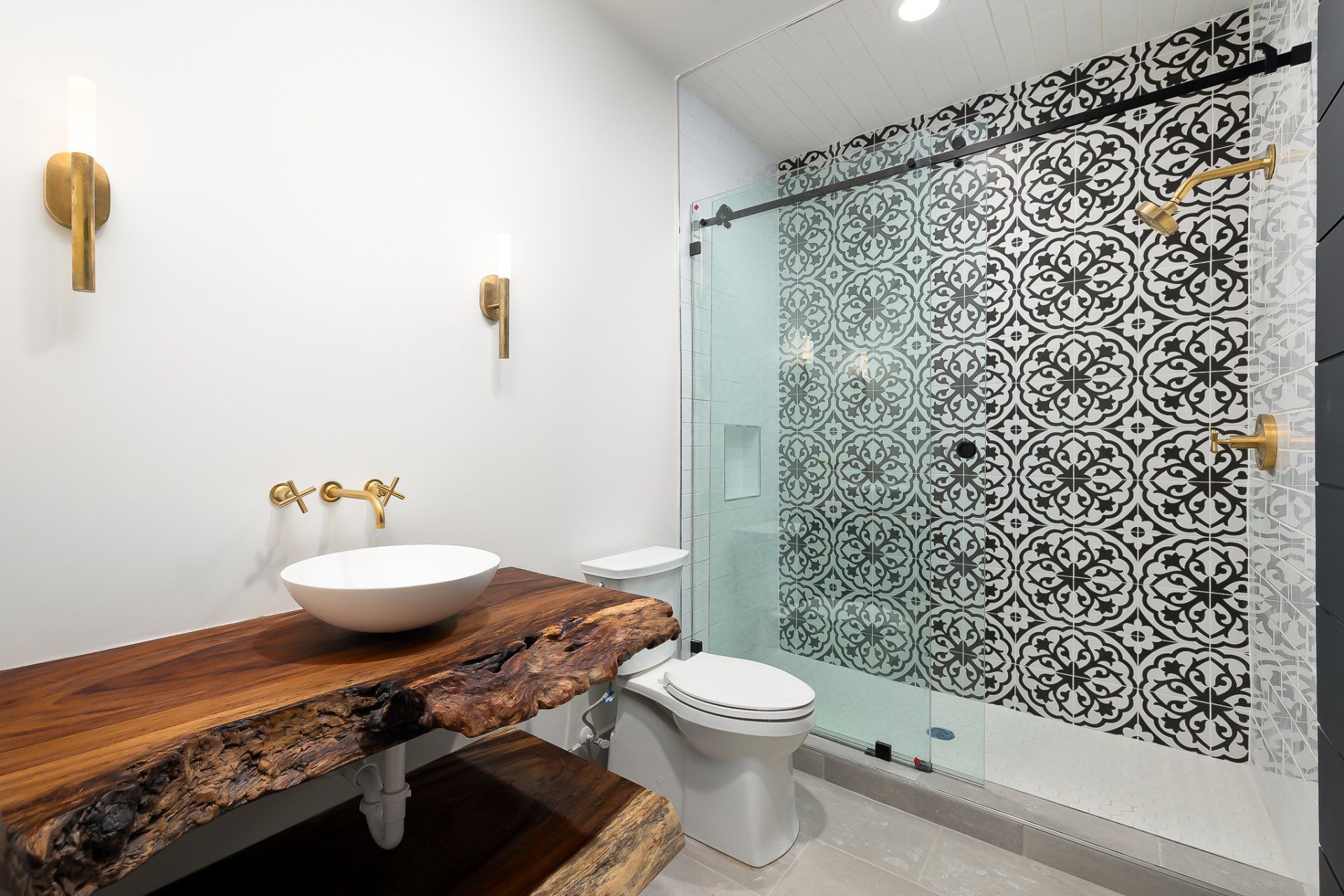 Modern bathroom with wood vanity, vessel sink, toilet, and patterned glass shower door
