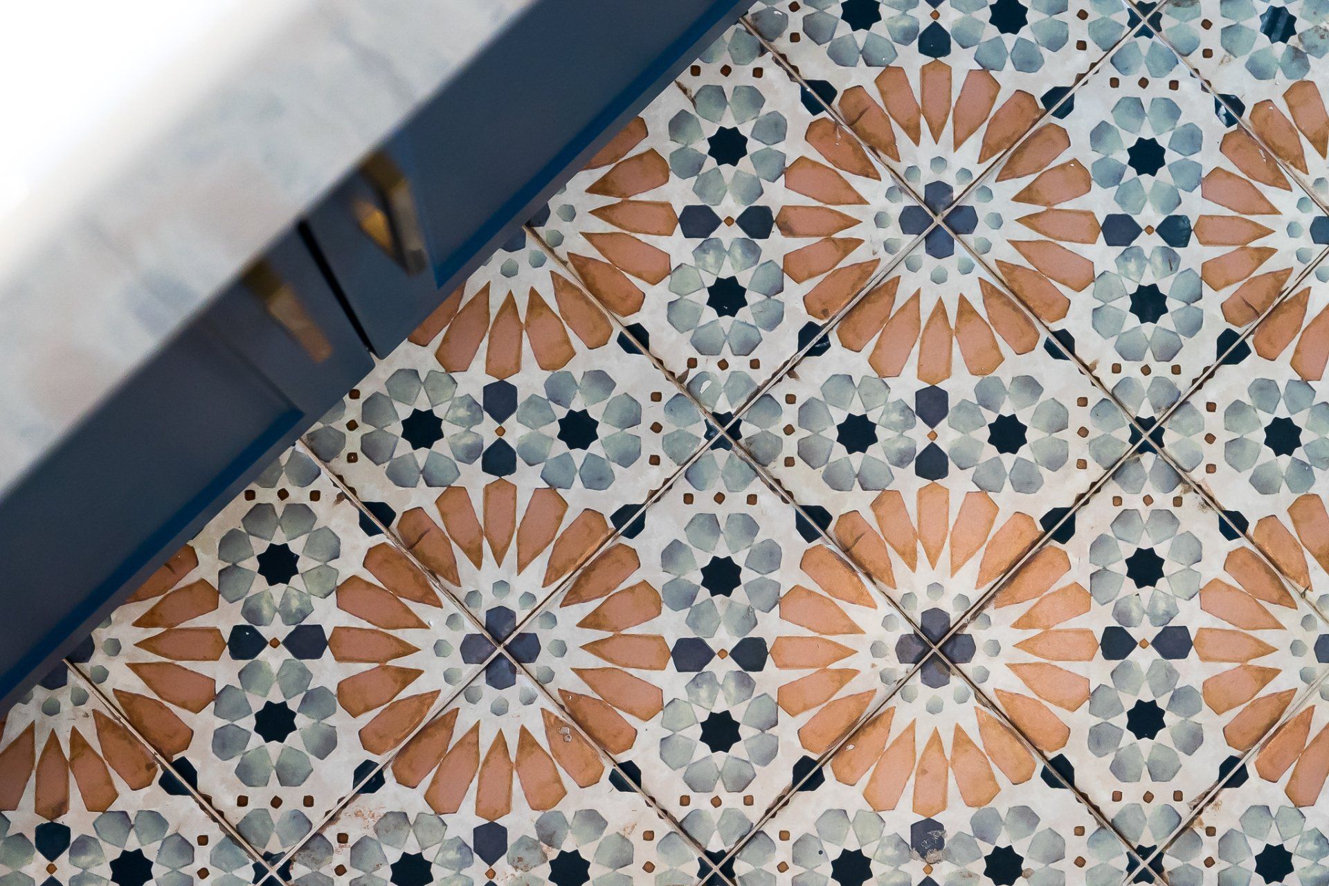 Diagonal view of patterned floor tiles in blue, gray, and terracotta tones