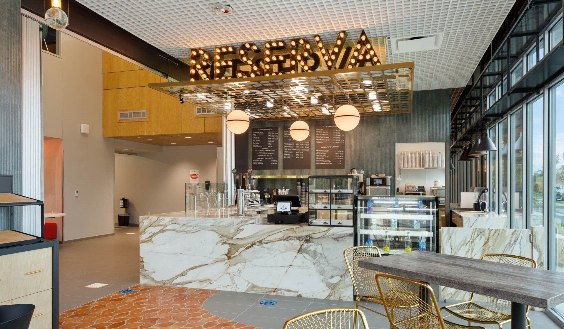 Modern café interior with marble tables, warm pendant lights, and a glass pastry display counter