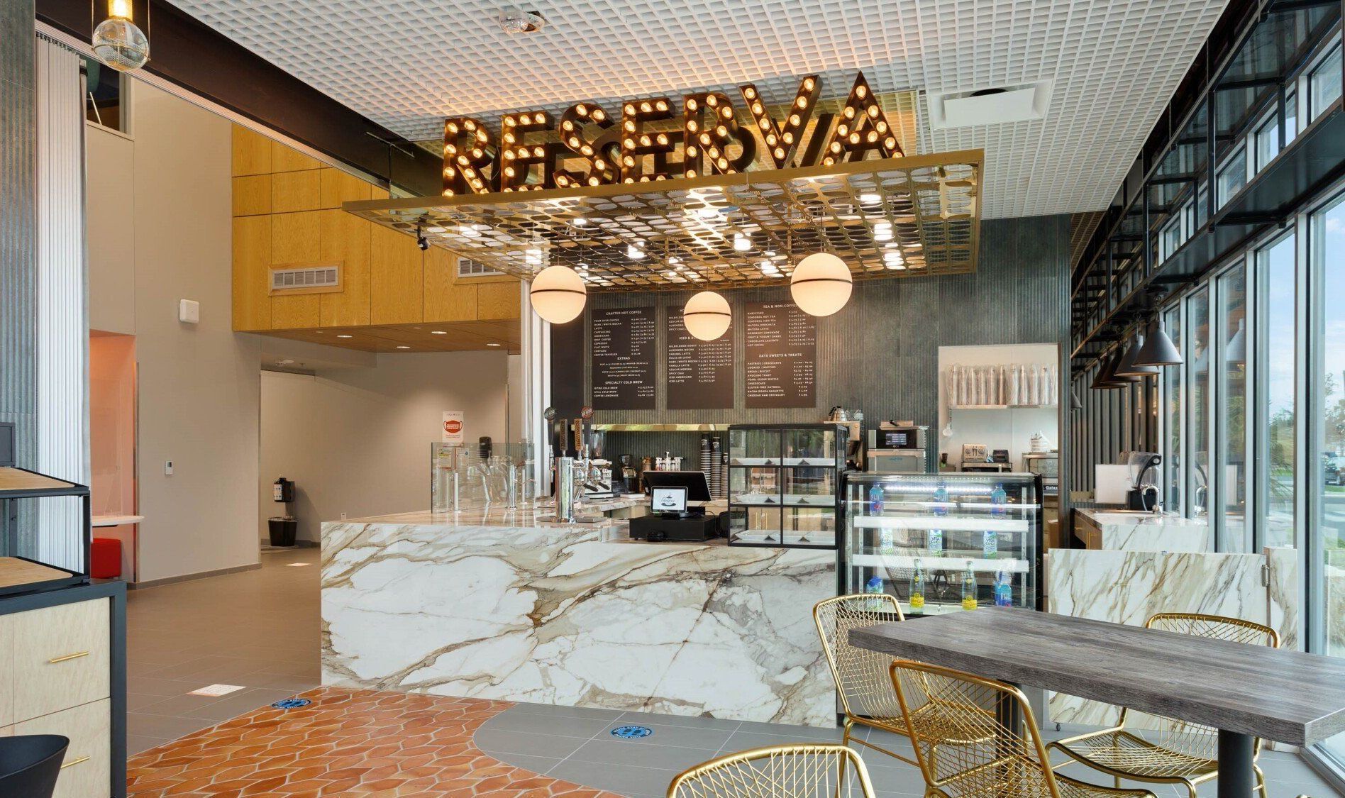 Modern café interior with marble counter, warm pendant lights, and glass display case