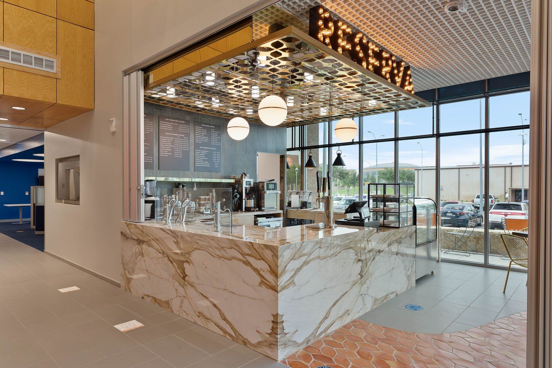 Modern office lounge with marble counter, glass walls, and hanging globe lights