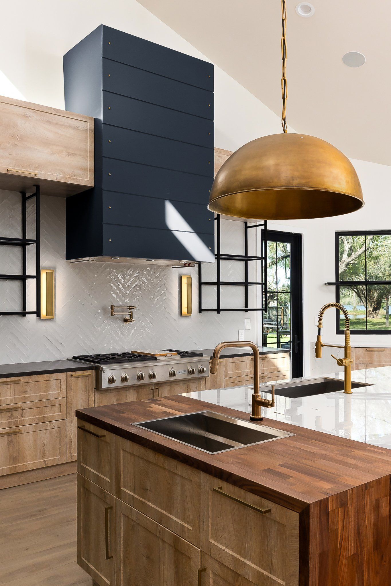 Modern kitchen with wood island, brass pendant light, gray cabinets, and large windows