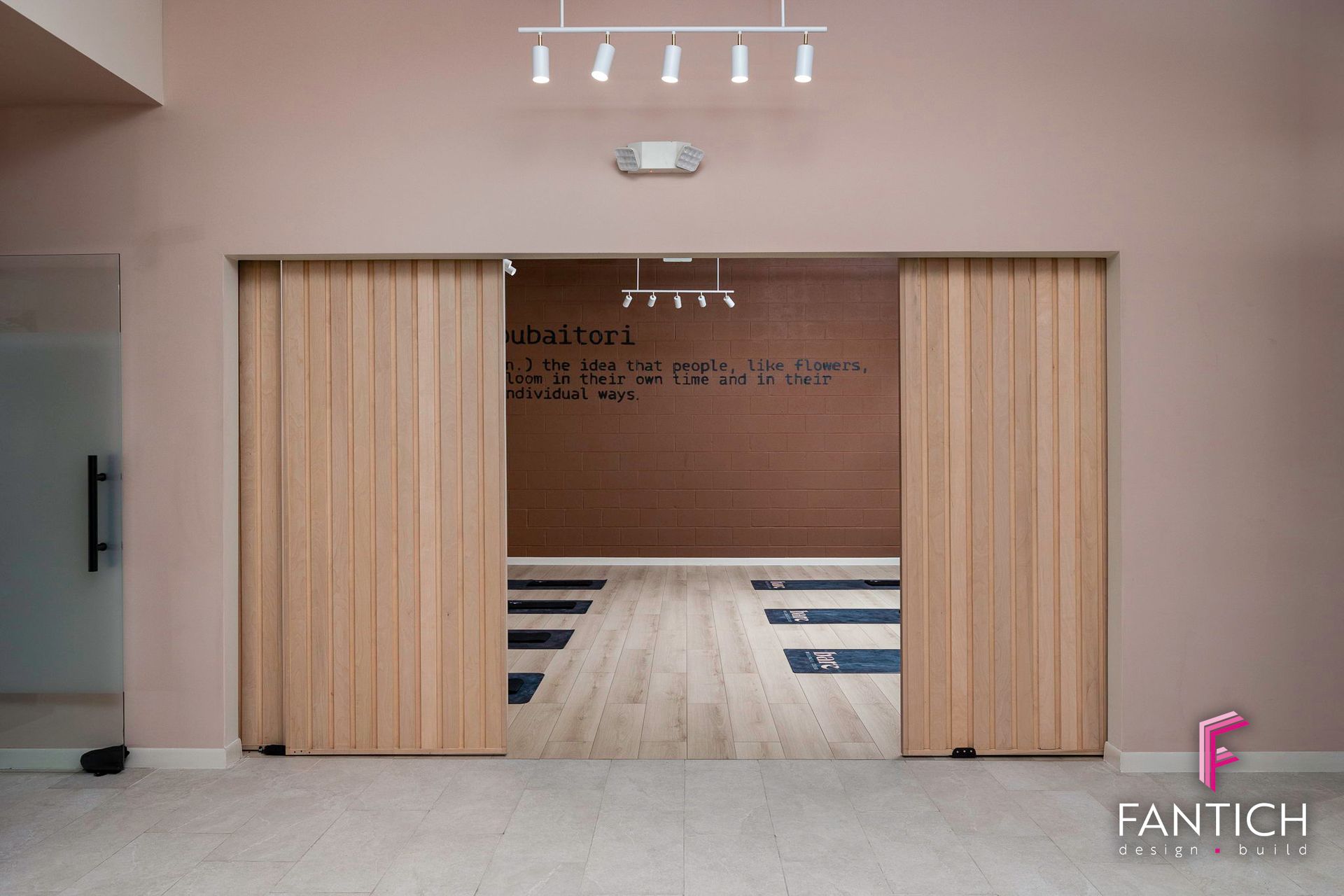 Modern office entrance with sliding wooden doors and a reception area beyond.