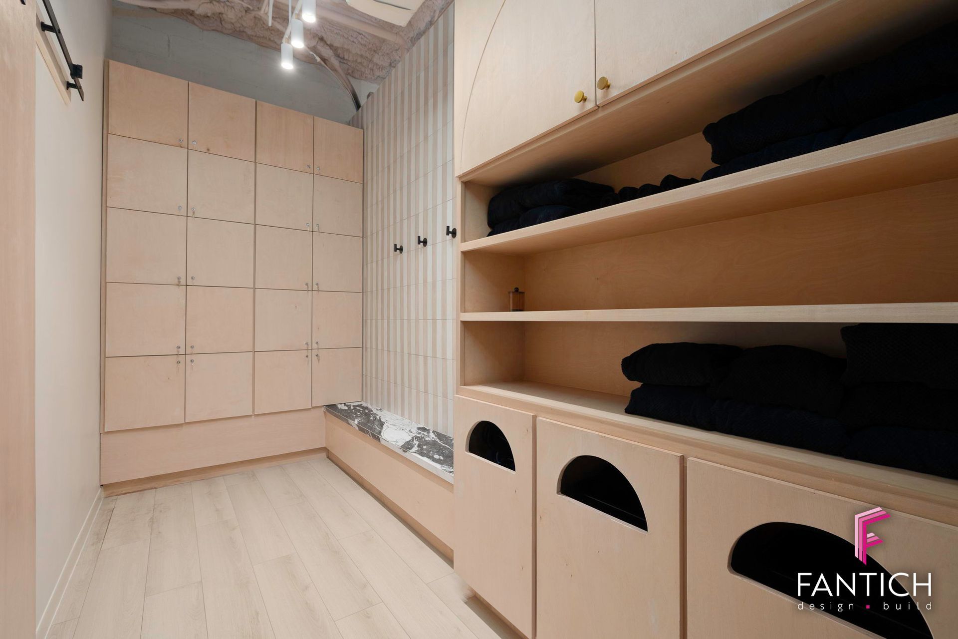 Walk-in closet with beige shelves, built-in drawers, and hanging storage in a bright, narrow room