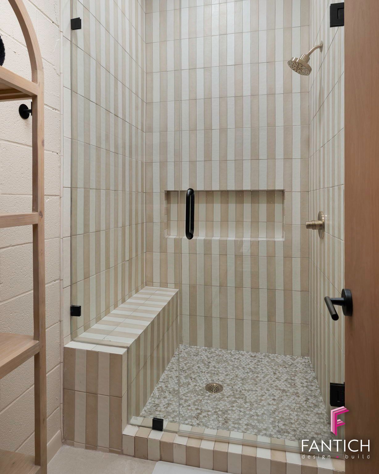 Modern tiled walk-in shower with built-in bench, niche, and pebble floor.