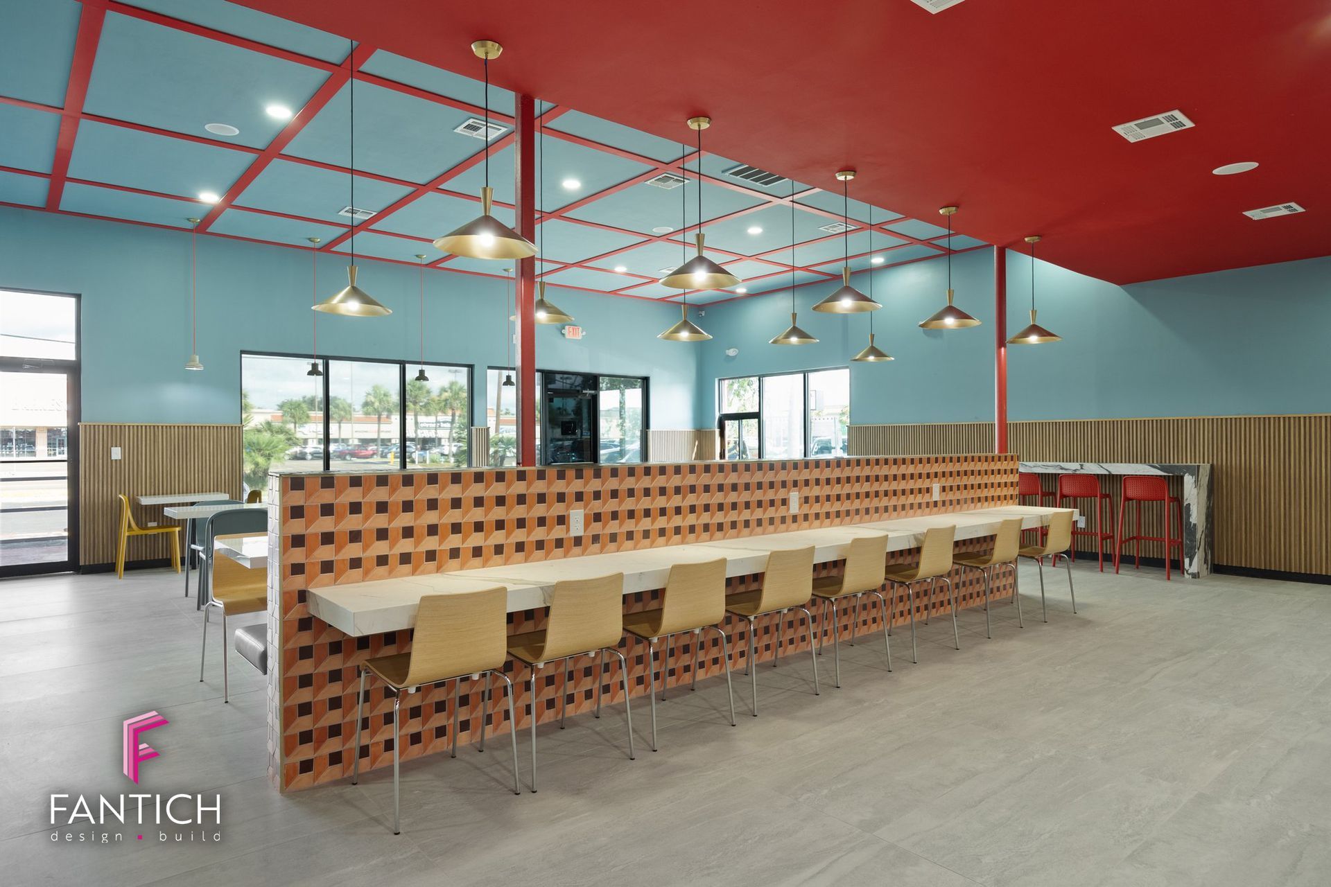 Modern café interior with red ceiling, blue walls, long communal table, and white bar stools