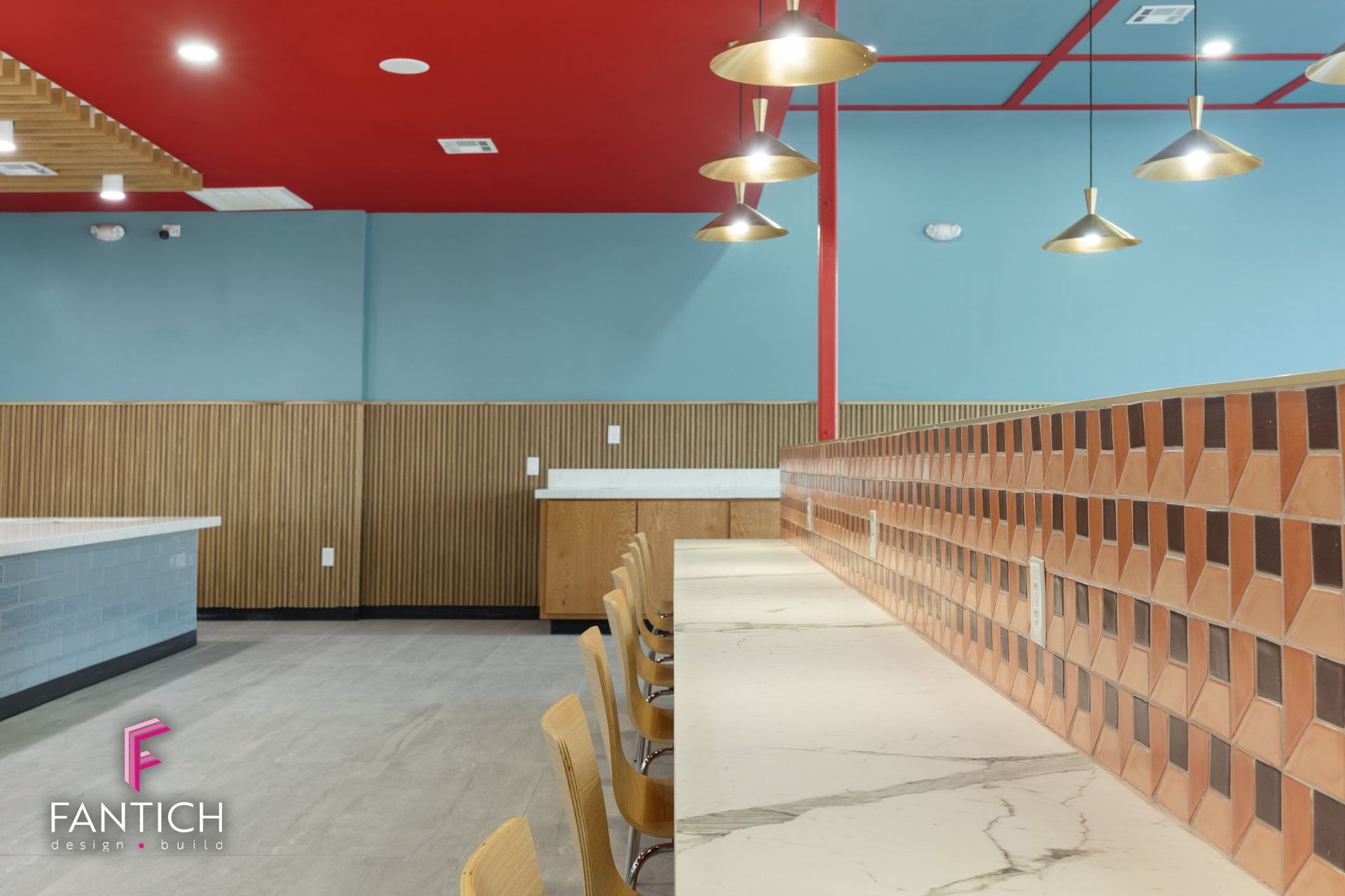 Modern cafeteria interior with red ceiling, blue walls, wood paneling, and marble counter seating