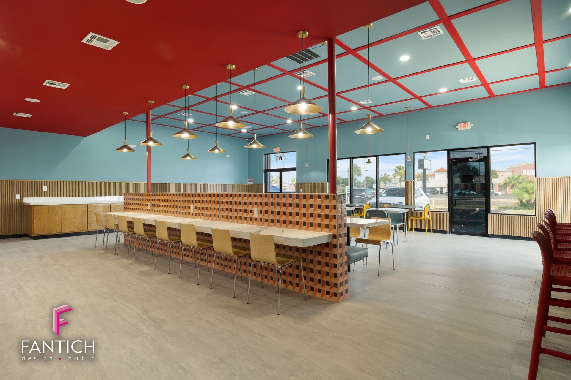 Empty modern restaurant with wood tables, red ceiling beams, blue walls, and pendant lights