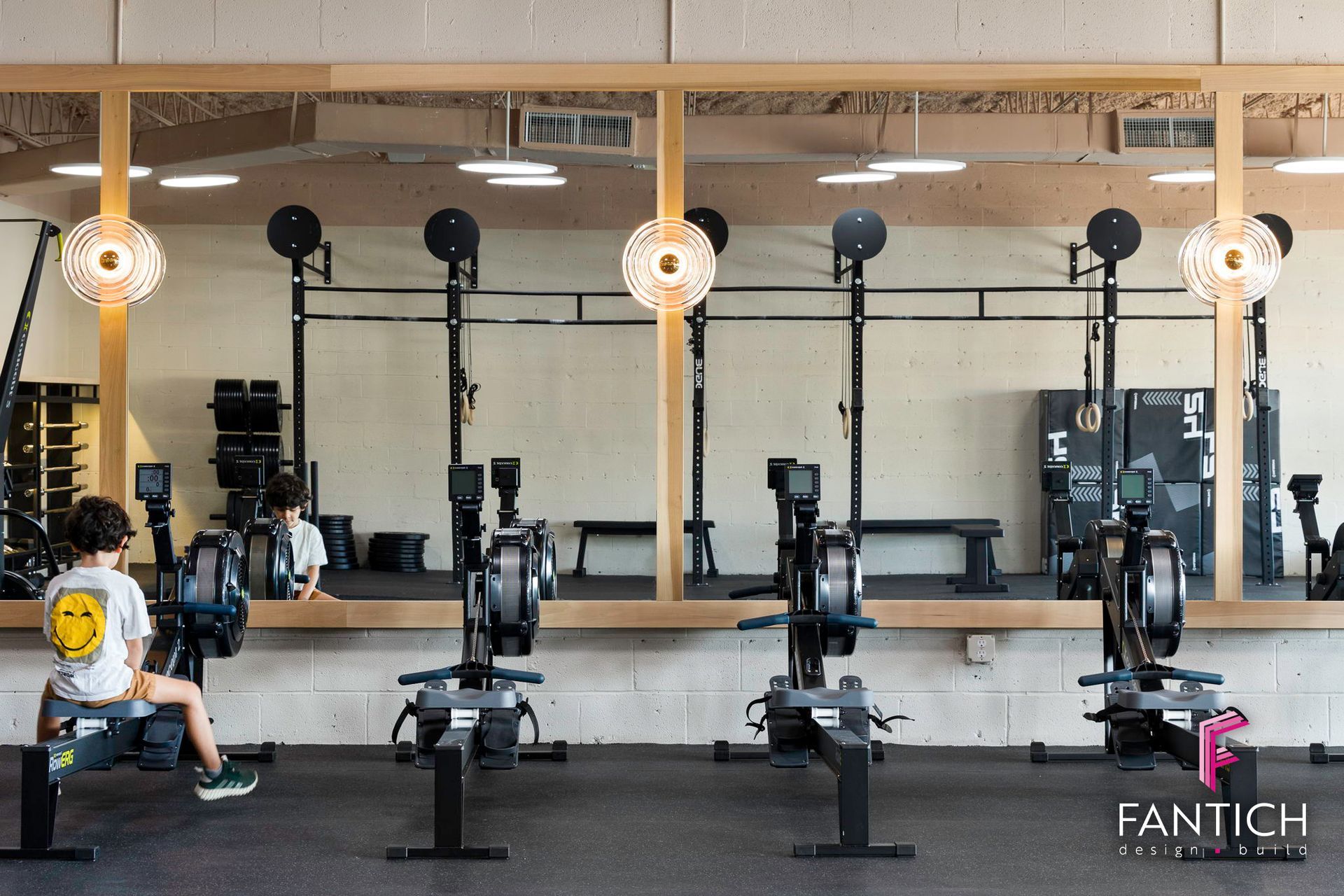 Gym studio with rowers and stationary bikes facing a mirrored wall