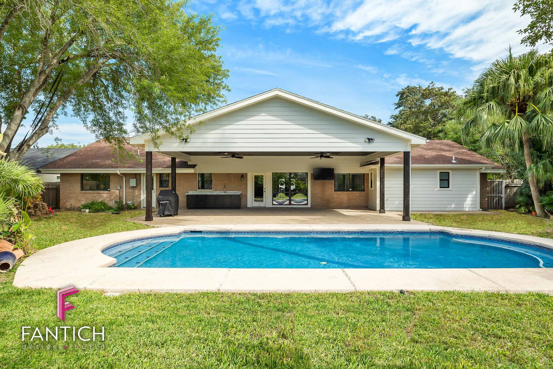 Luxury home with covered patio and a blue swimming pool in a landscaped backyard